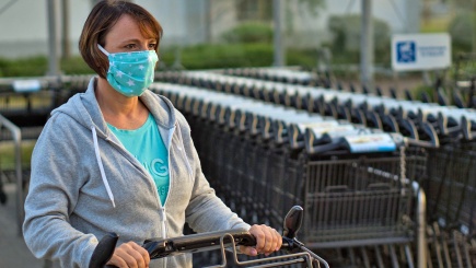 Frau mit Mundschutz schiebt einen Einkaufswagen