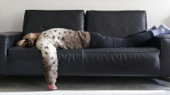 Frau liegt schlapp auf Sofa