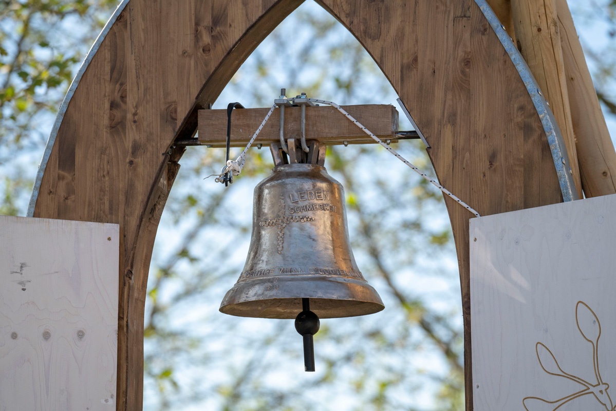 Eine Glocke hängt am Eingang des Kirchengartens