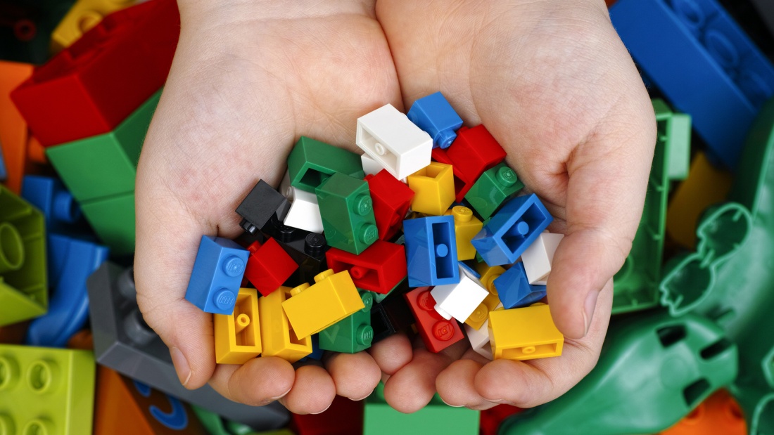 Kind hält bunte Lego-Steine in der Hand