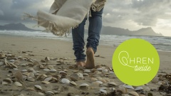 Frau läuft barfuß am Strand