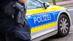 Ein Polizist im Einsatz mit Polizeiauto