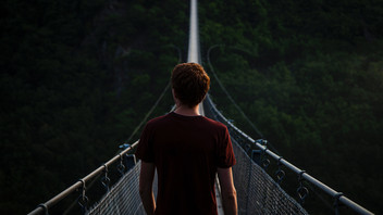 Mann steht vor schmaler Hängebrücke