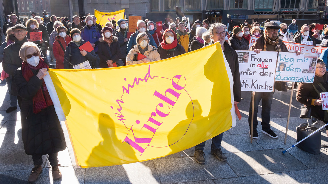 Demonstranten mit einem "Wir sind Kirche" Plakat.