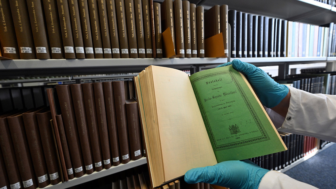 Mitarbeiterin hält in Universitäts- und Landesbibliothek Düsseldorf Buch mit grüner Seite
