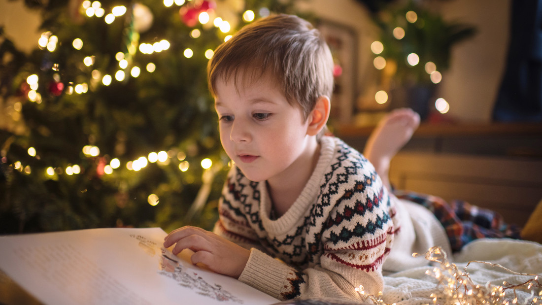 Junge liest vor Weihnachtsbaum