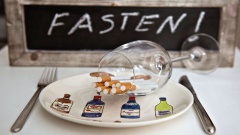 Symbolfoto zum Thema "Fasten" mit leerem Teller, Weinglas und Zigaretten