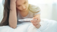 verzweifelte Frau mit positivem Schwangerschaftstest
