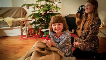 Zwei Mädchen untern Weihnachtsbaum mit Geschenken