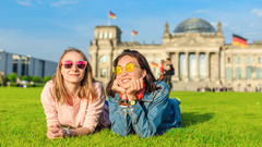 Glückliche Jugendliche liegen auf der Wiese vor dem Deutschen Reichstag