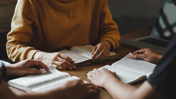 Drei junge Menschen mit Bibel  sprechen untereinander