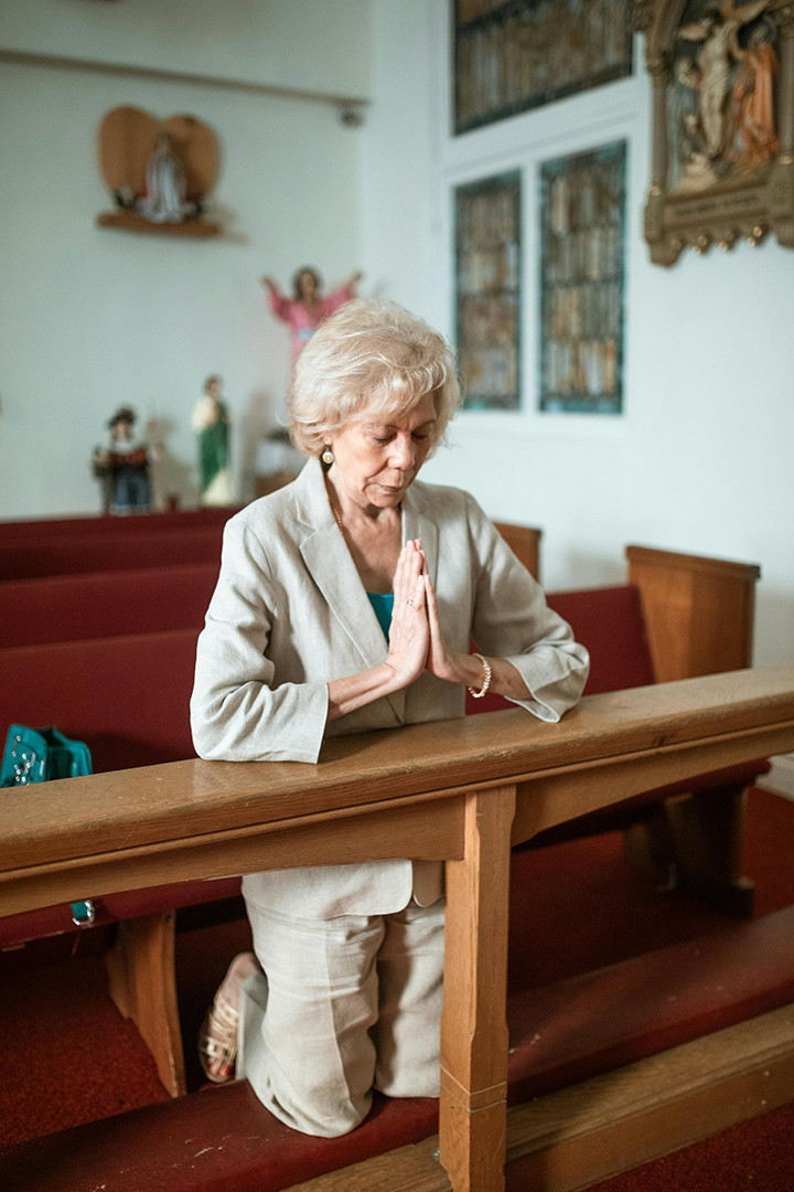 Frau kniend in Kirchenbank