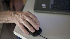 Hand eines älteren Menschn ruht auf einer Computer-Maus