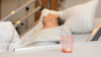 Tabletten im Becher vor Krankenhausbett