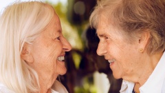 Zwei ältere Frauen stehen sich gegenüber und sehen sich an, sie lachen