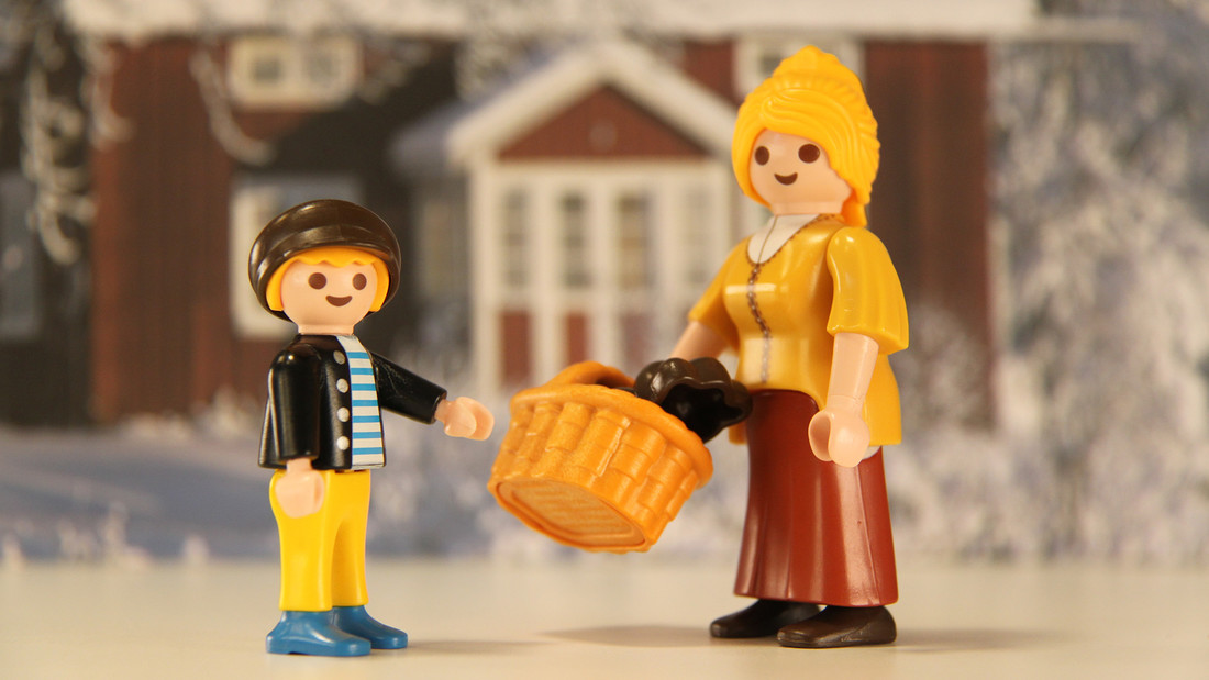 Ein Junge nimmt von einer Frau einen Korb entgegen (Playmobil-Figuren)