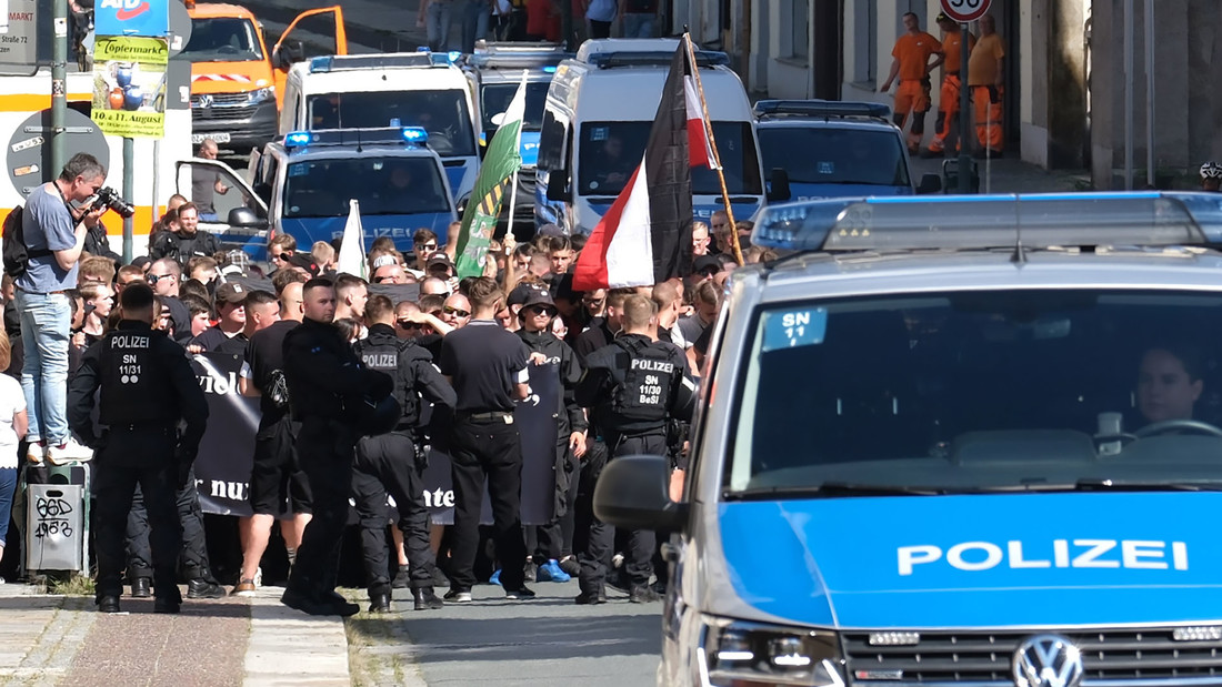 Rechte Gegendemonstration auf einer Strasse, die von Polizei begleitet wied.