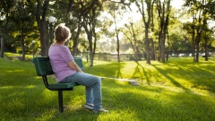 Frau sitzt allein auch einer Parkbank