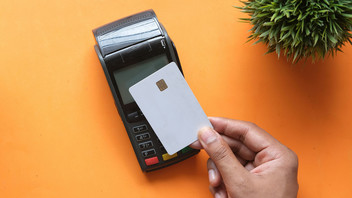 Eine Hand hält eine Kreditkarte auf ein Zahlungsgerät.