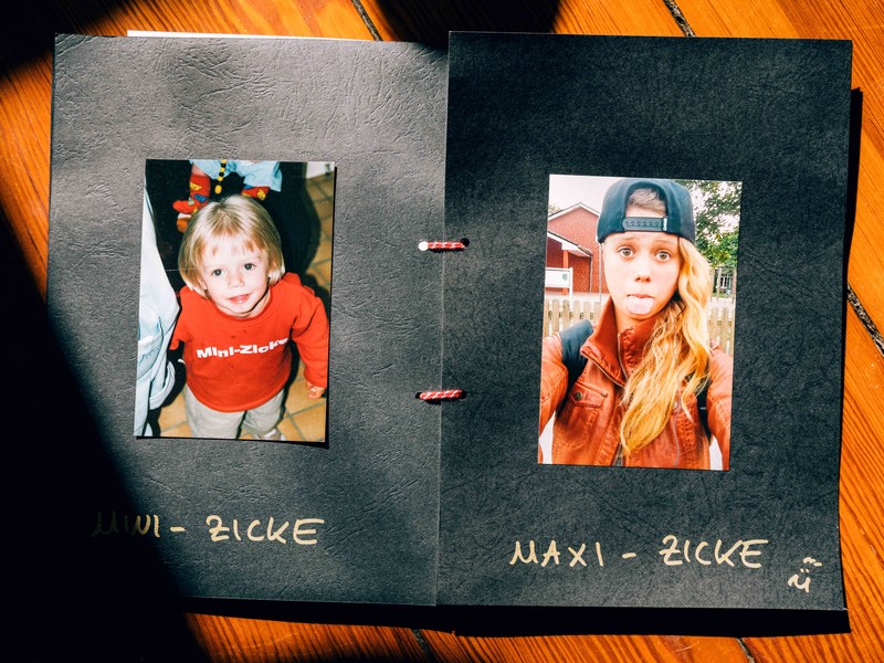 Ein selbstgebasteltes kleines Fotobuch zeigt Fotos von Mia als Kleinkind in rotem Pulli und Teenager mit rausgestreckter Zunge, einmal betitelt als "Mini-Zicke" und einmal "Maxi-Zicke". Sie wurde 20 Jahre alt
