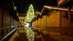 Weihnachtsbaum des Weihnachtsmarktes spiegelt sich auf einer regennassen Tischplatte