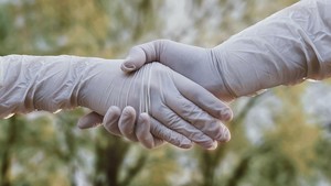 Zwei Hände mit Gummihandschuhen