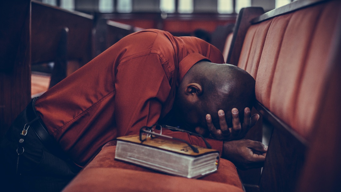 Mann betet auf Kirchbank