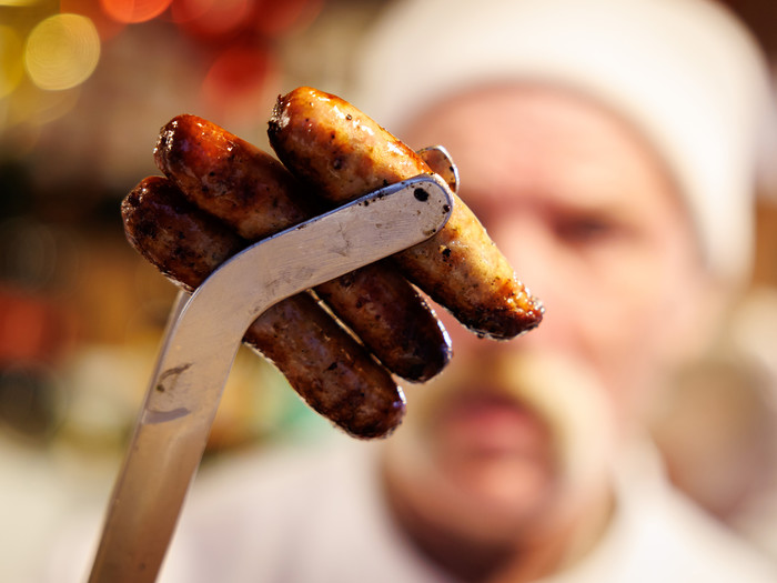 Nürnberger Bratwürste stecken auf dem Nürnberger Christkindlesmarkt in einer Grillzange