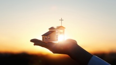 Miniatur Kirchengebäude auf einer Hand im Sonnenlicht