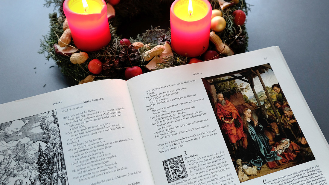 Weihnachtsgeschichte in der Bibel neben Adventskranz