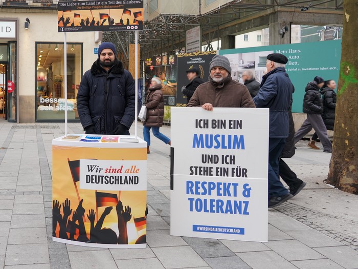 München, zwei muslimische Männer werben an einem Informationsstand mit Botschaften, die für Respekt, Toleranz und Einigkeit. Auf einem Transparent ist zu lesen: "Wir sind alle Deutschland"