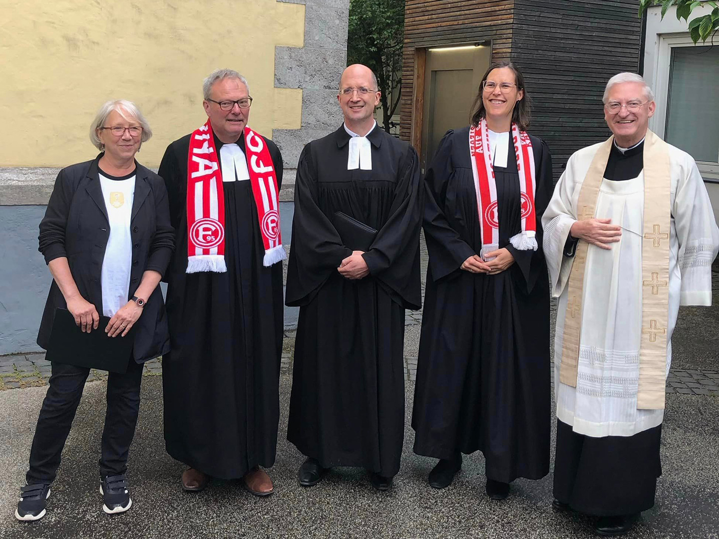 Gruppenfoto mit Geistlichen mit Fußballschals