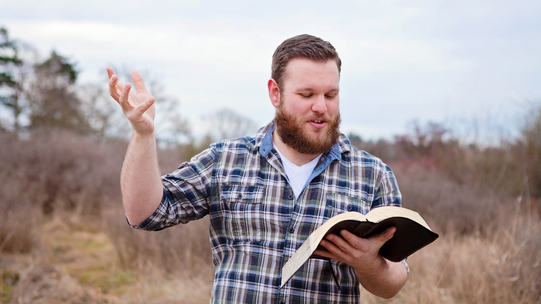 Mann auf freiem Feld predigt mit Bibel