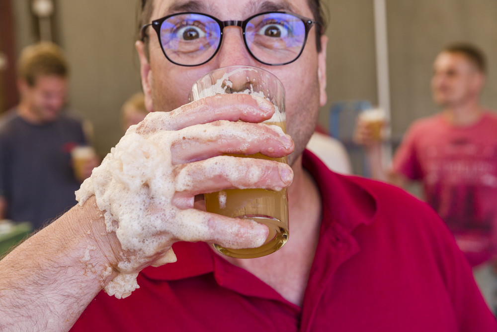 Mann trinkt Apfelsaft aus schaumigem Glas