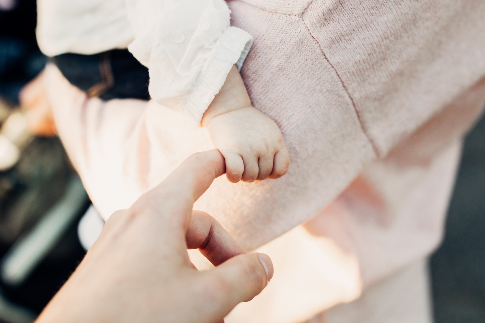 Ein Baby hält den Finger seiner Mutter fest umklammert.