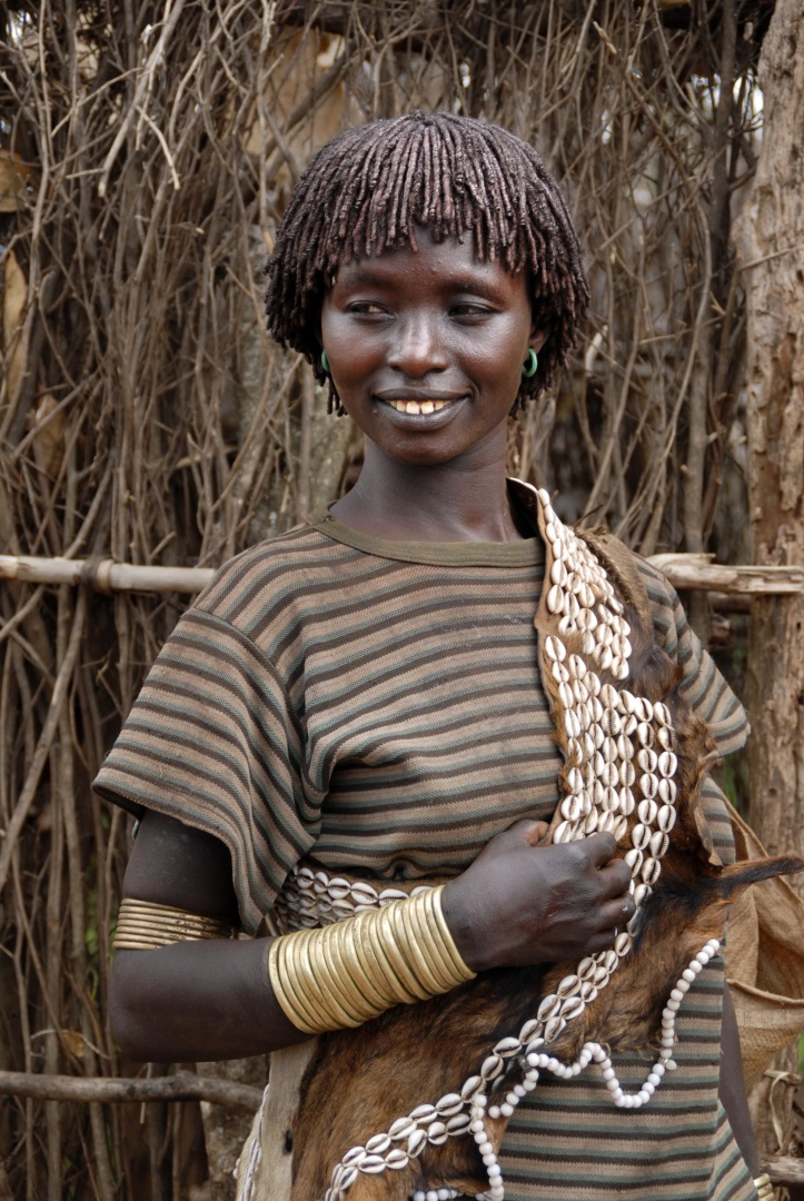 Portrait einer jungen Frau mit einer traditionellen afrikanischen Frisur und einer Kette aus Kaurimuscheln auf dem Markt von Keyafer Äthiopien