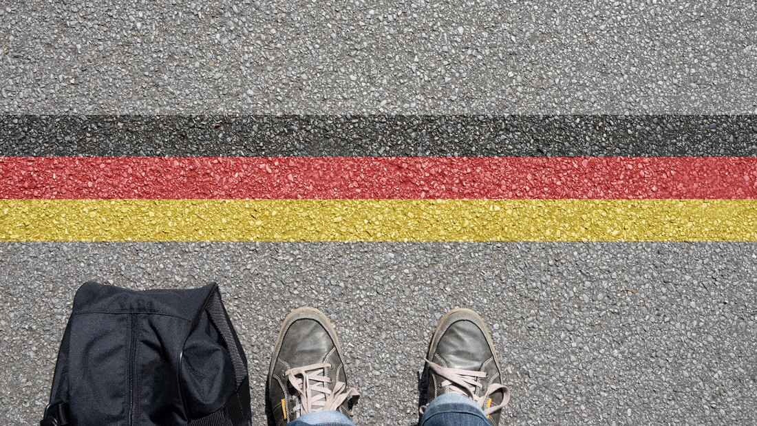 Füße mit Tasche auf Asphalt mit Deutschlandfahne