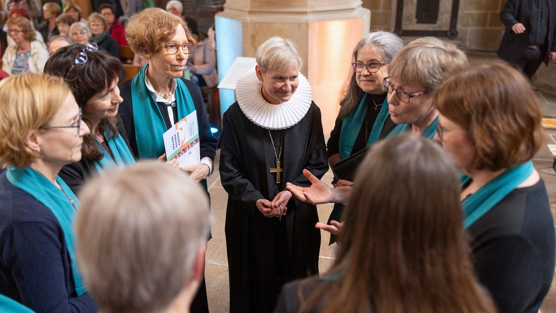 Bischöfin Kirsten Fehrs im Talar steht in einem Kreis mit Frauen in einer Kirche