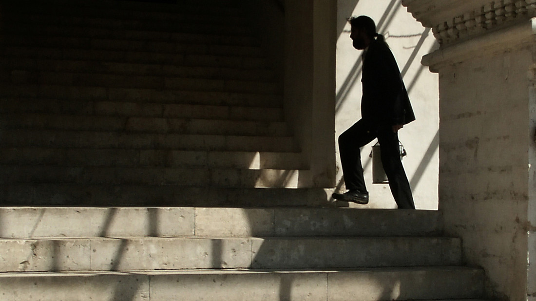 Eine Person läuft im Schatten eine Treppe hinauf.