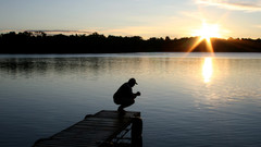 Mann betet im Sonnenuntergang am See