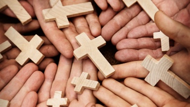 Viele Hände halten gemeinsam viele Kreuze