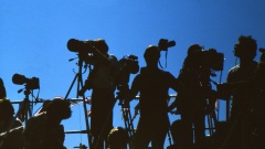 Pressefotografen als Silhouetten vor blauem Himmel