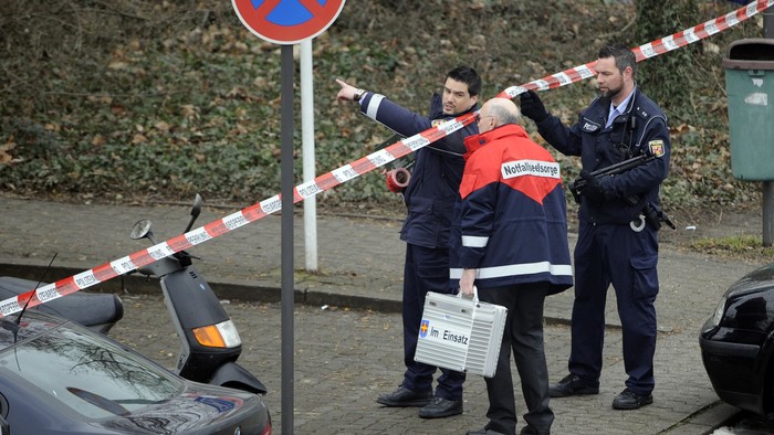 Polizisten und ein Notfallseelsorger stehen an einer Absperrung vor einer Berufsschule in Ludwigshafen