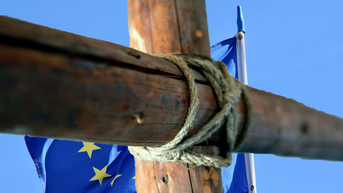 Ein Holzkreuz vor der Europaflagge