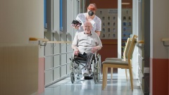 Ausgebildete Pflegefachkraft schiebt Mann im Rollstuhl