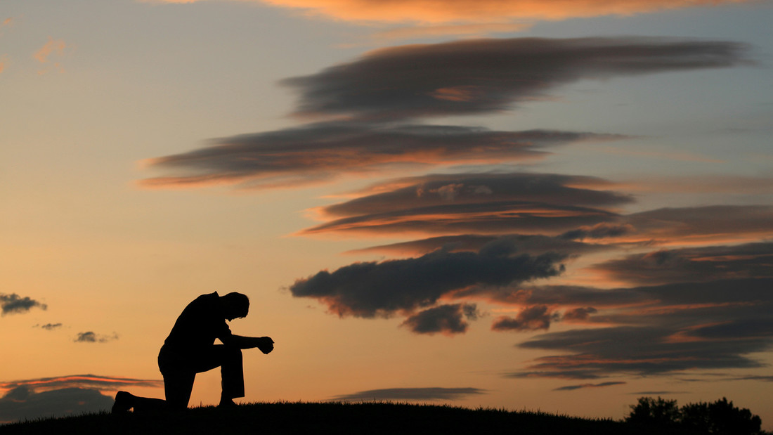 Mann betet vor Sonnenuntergang