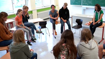 Schüler sitzen im Klassenraum und beten.