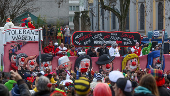 Viele Menschen laufen mit dem Toleranzwagen auf dem Rosenmontagszug in Düsseldorf mit.