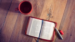 Bibel aufgeschlagen auf Tisch mit Tasse und Textmarker