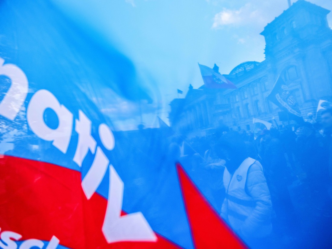 Menschen protestieren in Berlin mit AFD-Parteifahne gegen die steigenden Lebenshaltungskosten 